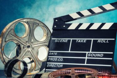 A Movie Clapboard And Movie Reel On Blue Background.
