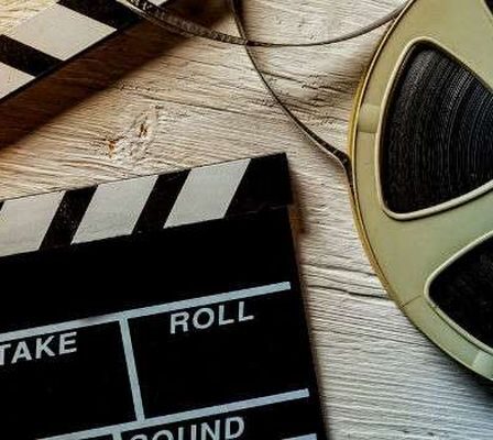 Movie Clapper And Film Reel On A Wooden Background.